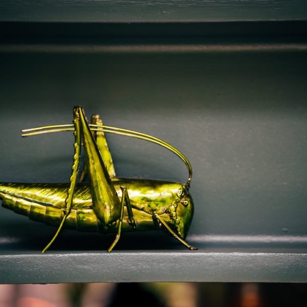 Textured metal grasshopper sculpture in a vibrant green finish.