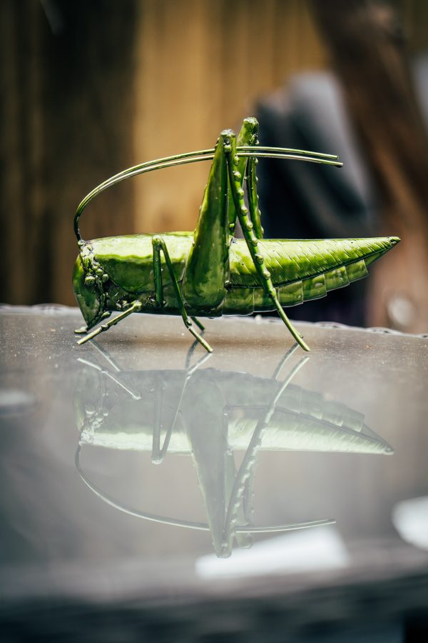 vibrant green grasshopper sculpture crafted from metal.