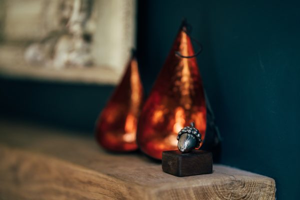 Gleaming metal acorn sculpture perched on a rustic wooden base adds a touch of nature to your space.