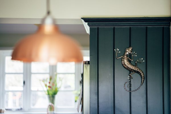 Modern gecko sculpture crafted from stainless steel, mounted on the wall.