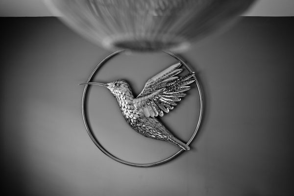 Delicate hummingbird sculpture crafted from stainless steel, mounted on the wall.