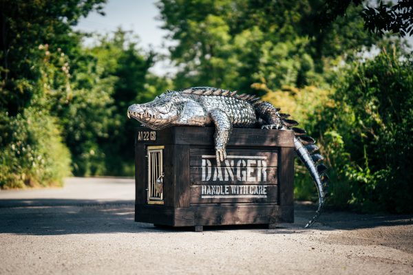 A stainless steel crocodile basks in the sun, adding a touch of whimsy to the garden.